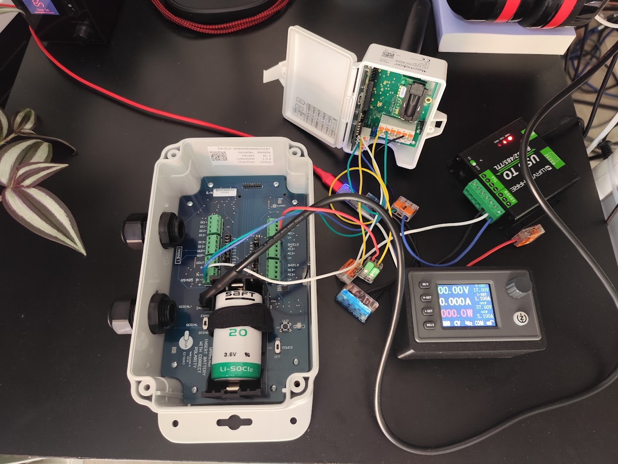 A device on the bench with its lithium thionyl chloride cell fitted, wired to a lab supply to measure real draw