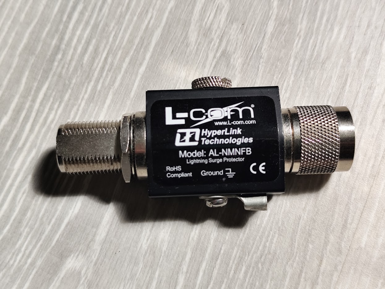 An L-com AL-NMNFB coaxial lightning surge protector, bulkhead mounted with its ground lug
