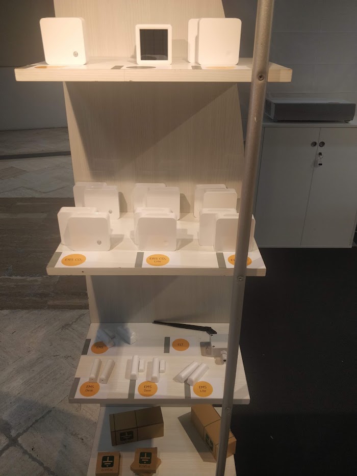 A display stand of indoor building sensors: CO2 monitors, door contacts and desk occupancy sensors