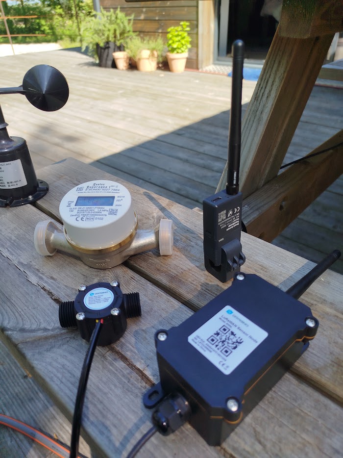 LoRaWAN metering and sensor devices, each carrying its DevEUI on a printed label and QR code