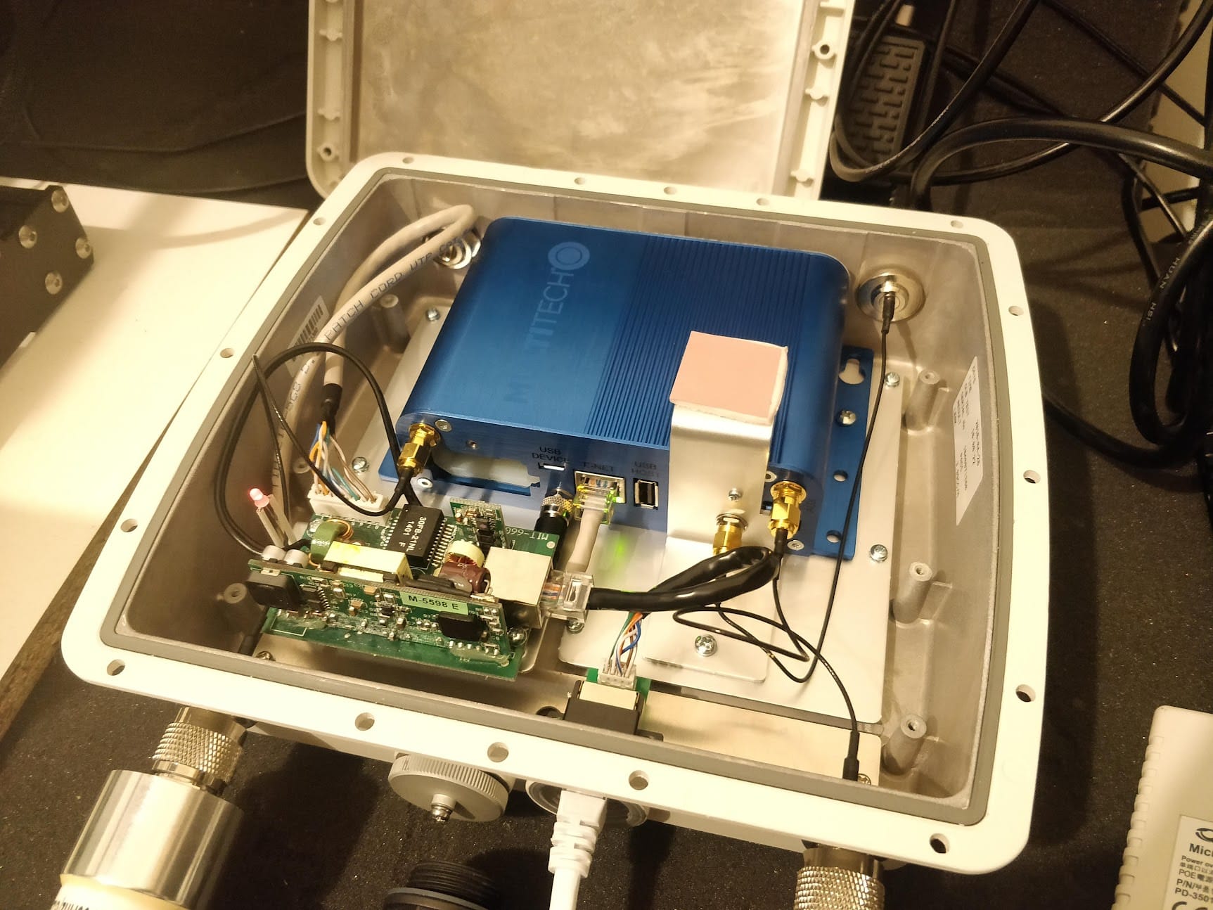 A gateway wired up in its enclosure, PoE and antenna feed connected