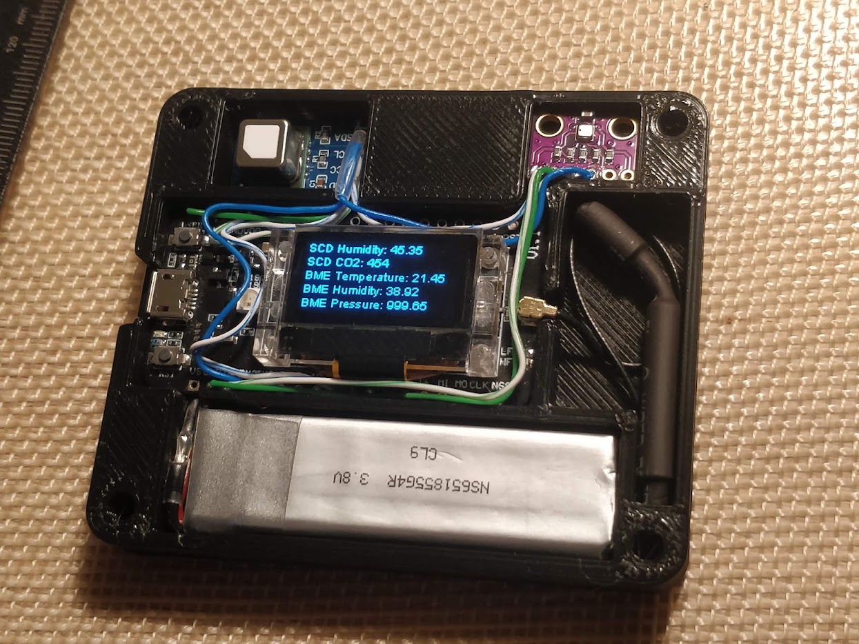 A prototype LoRaWAN CO2 sensor with its cover off, the display showing live CO2, temperature, humidity and pressure
